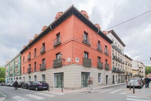 Un edificio con fachada roja, varios balcones y un paso de peatones.