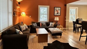 Ein gemütliches Wohnzimmer mit brauner Wand, Holzboden, einer Couch, einem Couchtisch und einem Teppich.