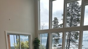 A spacious living room with a large window overlooking a lake, a sofa, a coffee table, and a chair.