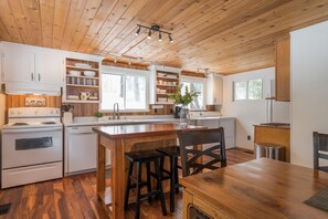 Una cocina tipo cabaña con armarios de madera, una isla central y un comedor.
