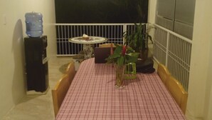 A dining area with a checkered tablecloth, a water dispenser, a potted plant, and a view of the outside. - Antelmi Inn (Plaridel)