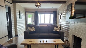 A cozy living room with a sofa, coffee table, and fireplace. - Cozy Beachfront Cottage (North Bay)