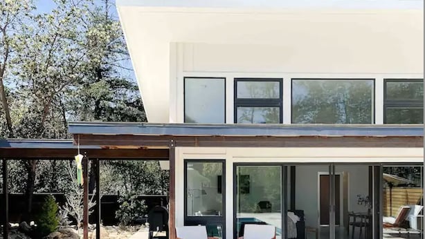 Une maison moderne dotée d’une piscine, d’un patio couvert et offrant une vue sur l’intérieur.