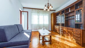 A living room with a sofa, a wooden coffee table, and a large wooden cabinet with glass doors.