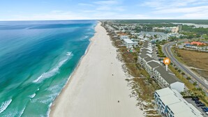 Une vue aérienne d’une zone côtière avec une plage, des bâtiments et une route.