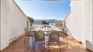 A terrace with a table set for four, surrounded by chairs, overlooking a cityscape. - Lake view apartment with 1 bedroom and community pool (Empuriabrava)