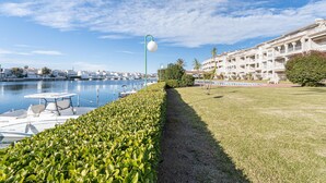 A marina with boats docked, a pathway, and a building with balconies. - Lake view apartment with 1 bedroom and community pool (Empuriabrava)