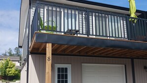 Ein zweistöckiges Gebäude mit einem überdachten Balkon, einer Garage und einem Schotterweg.