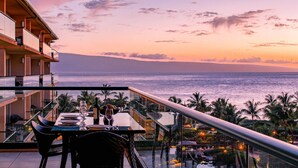 A dining area with a view of the ocean at sunset. - Maui Resort Rentals: Honua Kai Konea 609/13 - 4 Total Bedrooms, 6th Floor Deluxe Ocean Views! (Lahaina)