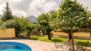 A swimming pool with a stone deck, surrounded by lush greenery and a view of mountains. - 3 bedroom country house with private pool and barbecue (Pollensa)