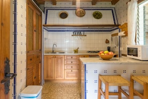 A compact kitchen with wooden cabinets, a sink, a stove, and a microwave. - 3 bedroom country house with private pool and barbecue (Pollensa)