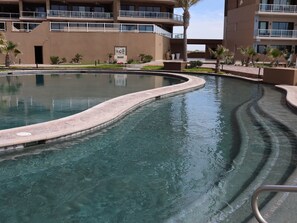 Relax by the pool surrounded by lush greenery and palm trees.