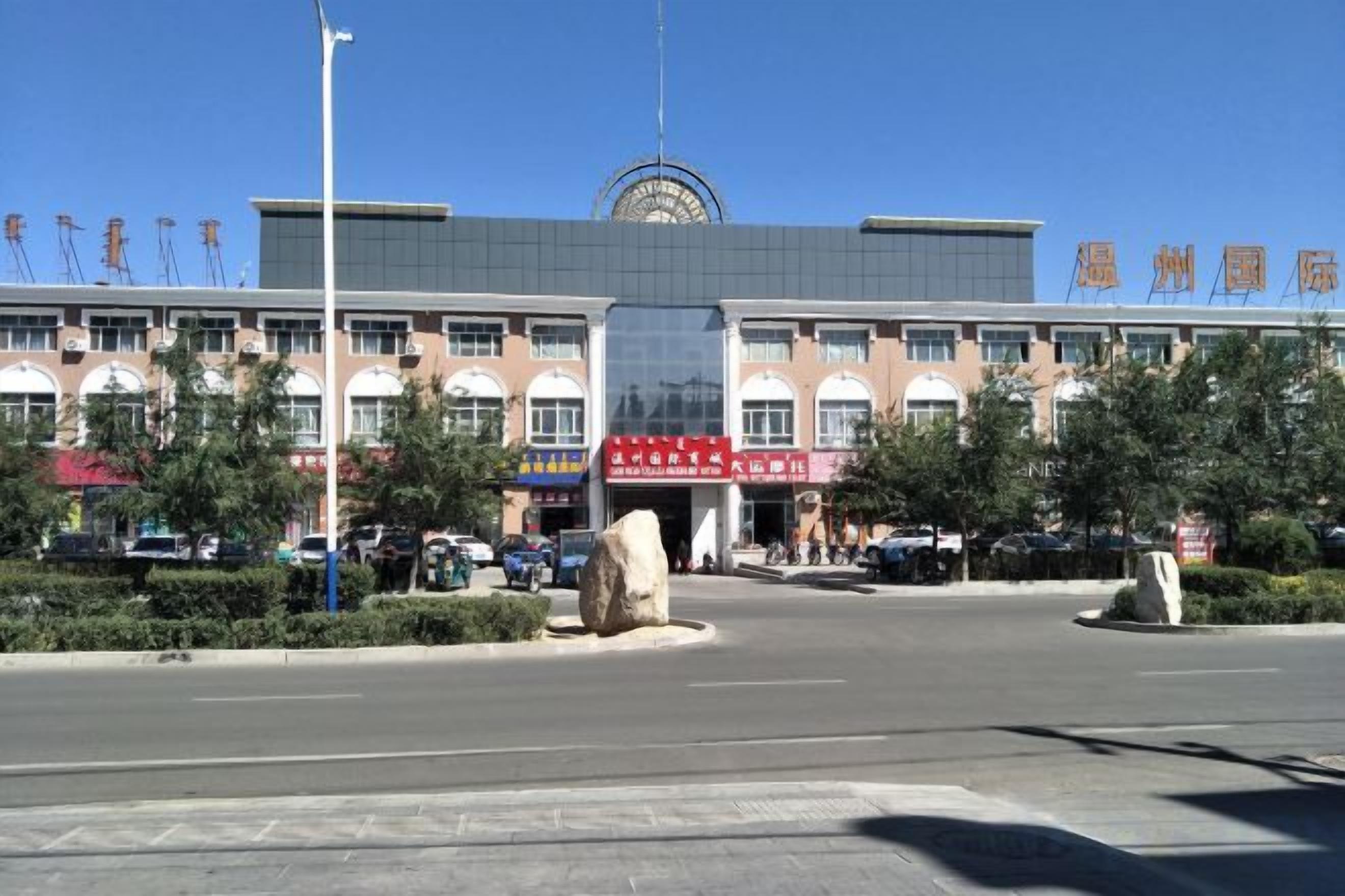 Un edificio de varios pisos con una entrada central, ventanas grandes y un cielo despejado.