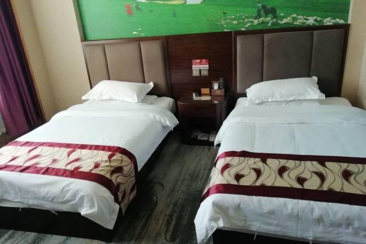 Une chambre d’hôtel avec deux lits, une tête de lit, une table de chevet et une horloge fixée au mur.