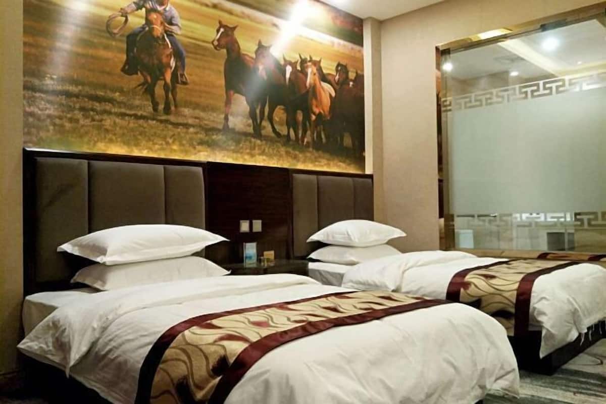Une chambre d’hôtel avec deux lits, une grande affiche de chevaux et un grand miroir.