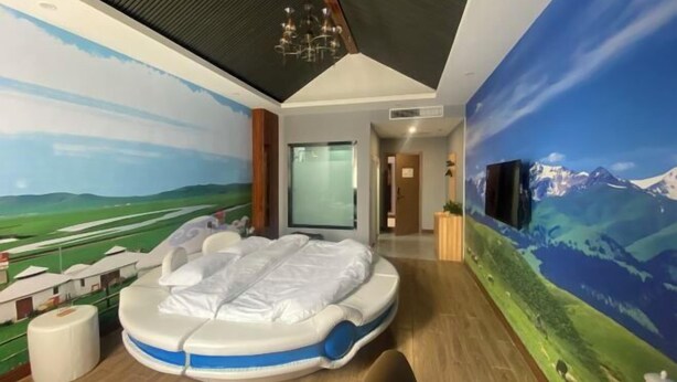 A room with a massage chair, a large mural of a landscape, and a television on the wall. - Moli International Hotel (Erenhot)