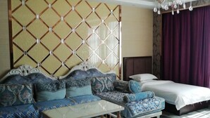 A bedroom with a large bed, a sofa, and a small table. - Moli International Hotel (Erenhot)