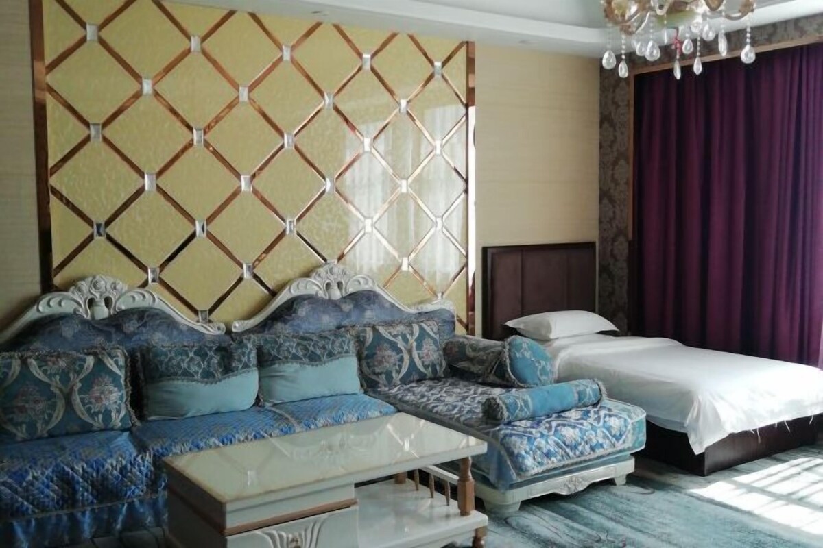 A bedroom with a large bed, a sofa, and a small table.