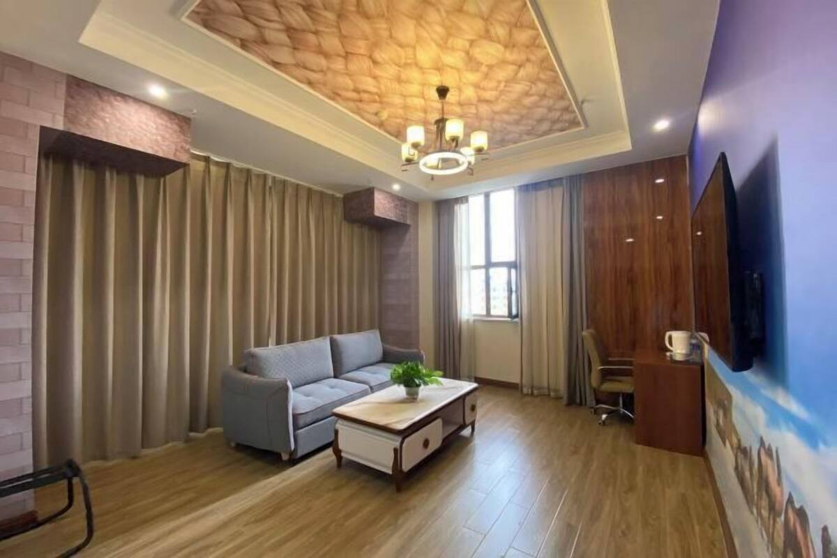 Un salon moderne avec un plafond en bois, un canapé gris, une table basse et un téléviseur fixé au mur.