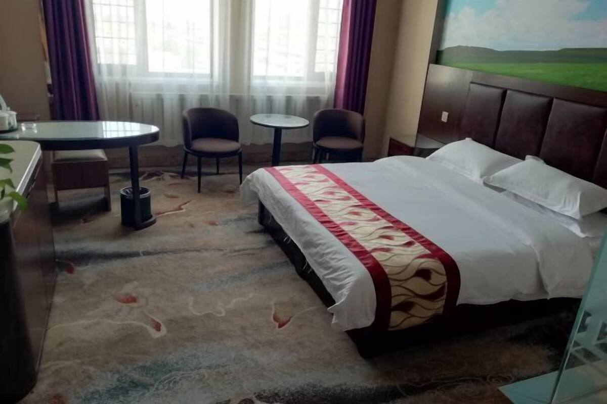 Une chambre d’hôtel avec un lit, un bureau, deux chaises et une petite table.