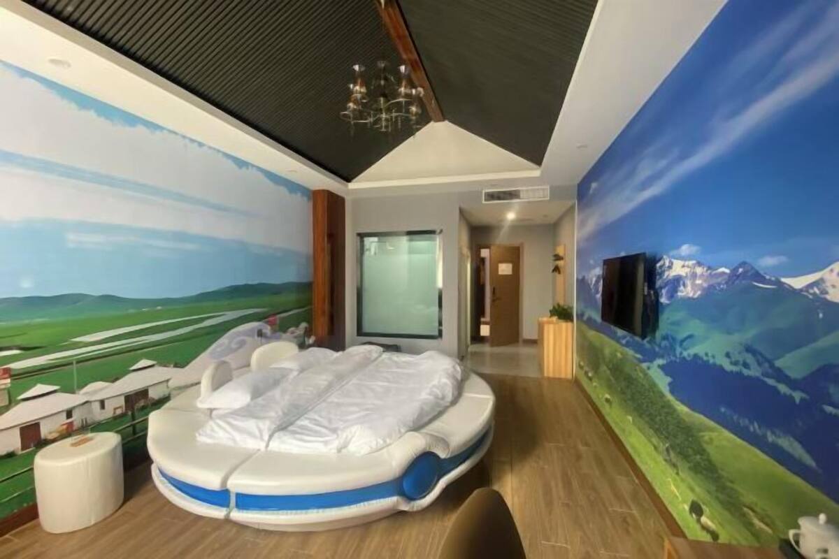 Une pièce avec une grande fresque représentant un paysage, un fauteuil de massage, un téléviseur et un plafond en bois.