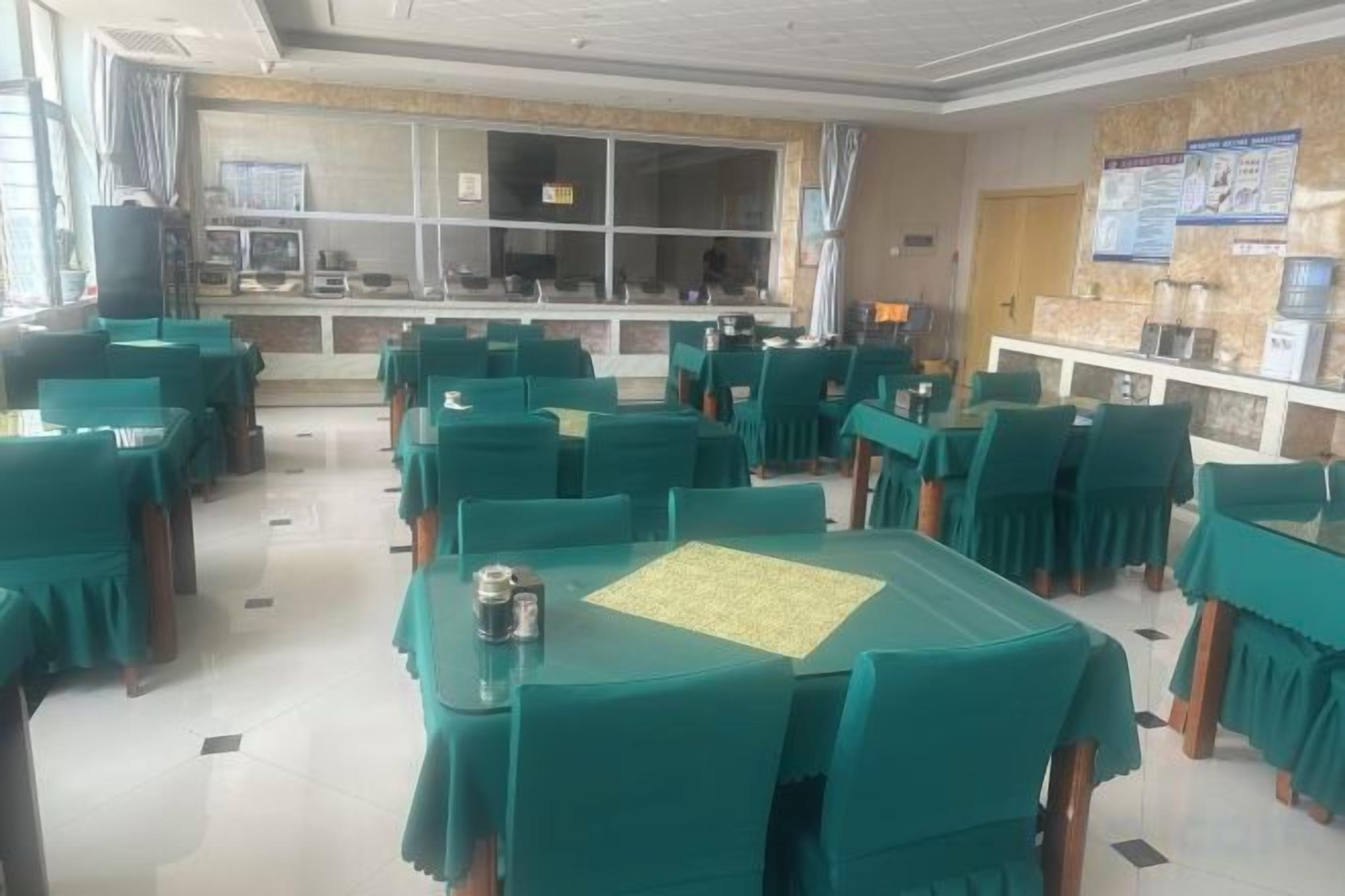 Un área de comedor con mesas y sillas, una ventana con cortinas y una barra con un tablero de menú.