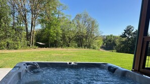 A hot tub with a view of a grassy area and trees.
