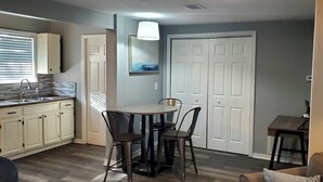 Una cucina compatta con zona pranzo, dotata di lavandino, pensili e un tavolo con sedie.