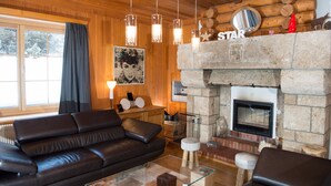 Una sala de estar acogedora con chimenea de piedra, sofá de cuero y una mesa de centro de vidrio.