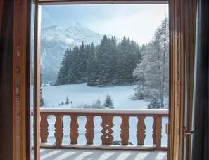 A snowy mountain landscape with a wooden balcony railing.