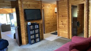 A log cabin interior with a television, bookshelf, and red sofa.