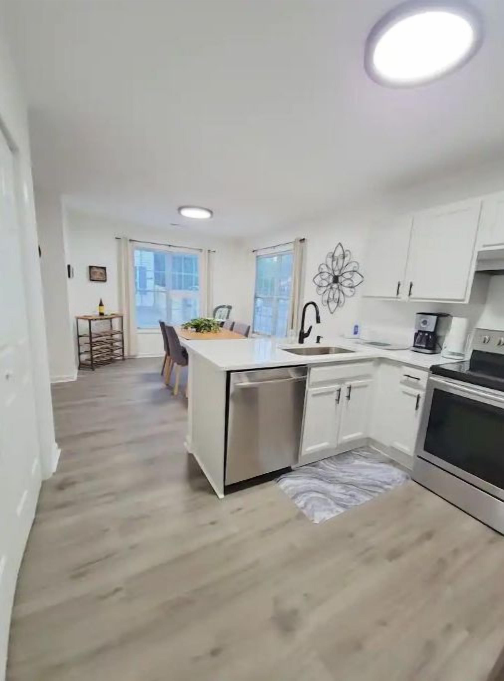 A modern kitchen with white cabinets, a central island, and a built-in oven.