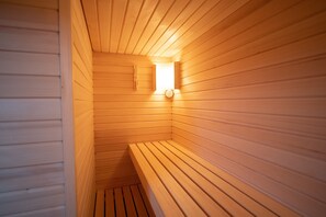 Una sauna con bancos de madera y un aplique en la pared.