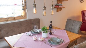 Een eetgedeelte met een houten tafel, comfortabele stoelen en een hanglamp.