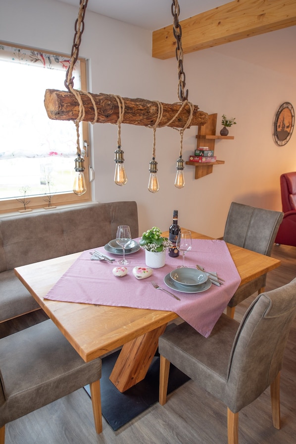 Un comedor con una mesa de madera, sillas acolchadas y una lámpara colgante.