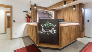 A reception desk with a wooden finish and a neon sign that reads 'Luisalle.' - Apartment 'Luisalle Top 1' with Mountain View, Shared Terrace and Wi-Fi (Auffach)