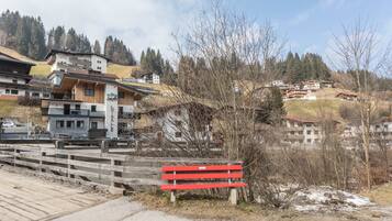 Un bâtiment sur lequel est affiché un panneau indiquant une vente, un banc rouge et une vue sur une zone vallonnée avec des arbres et d’autres bâtiments.