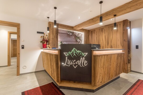 Un comptoir d’accueil avec un revêtement en bois et un panneau lumineux au néon sur lequel on peut lire « Luisalle ».