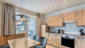 Eine moderne Küche mit Holzausbau, einem eingebauten Ofen und einem Essbereich mit Tisch und Stühlen.