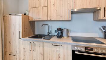 A kitchen with wooden cabinets, a sink, a coffee maker, and an oven.