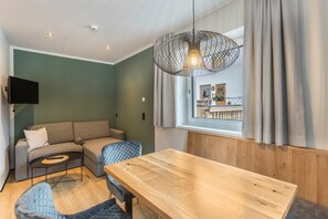 Una sala moderna con una mesa de comedor de madera, un sofá gris, un sillón azul y una lámpara colgante.