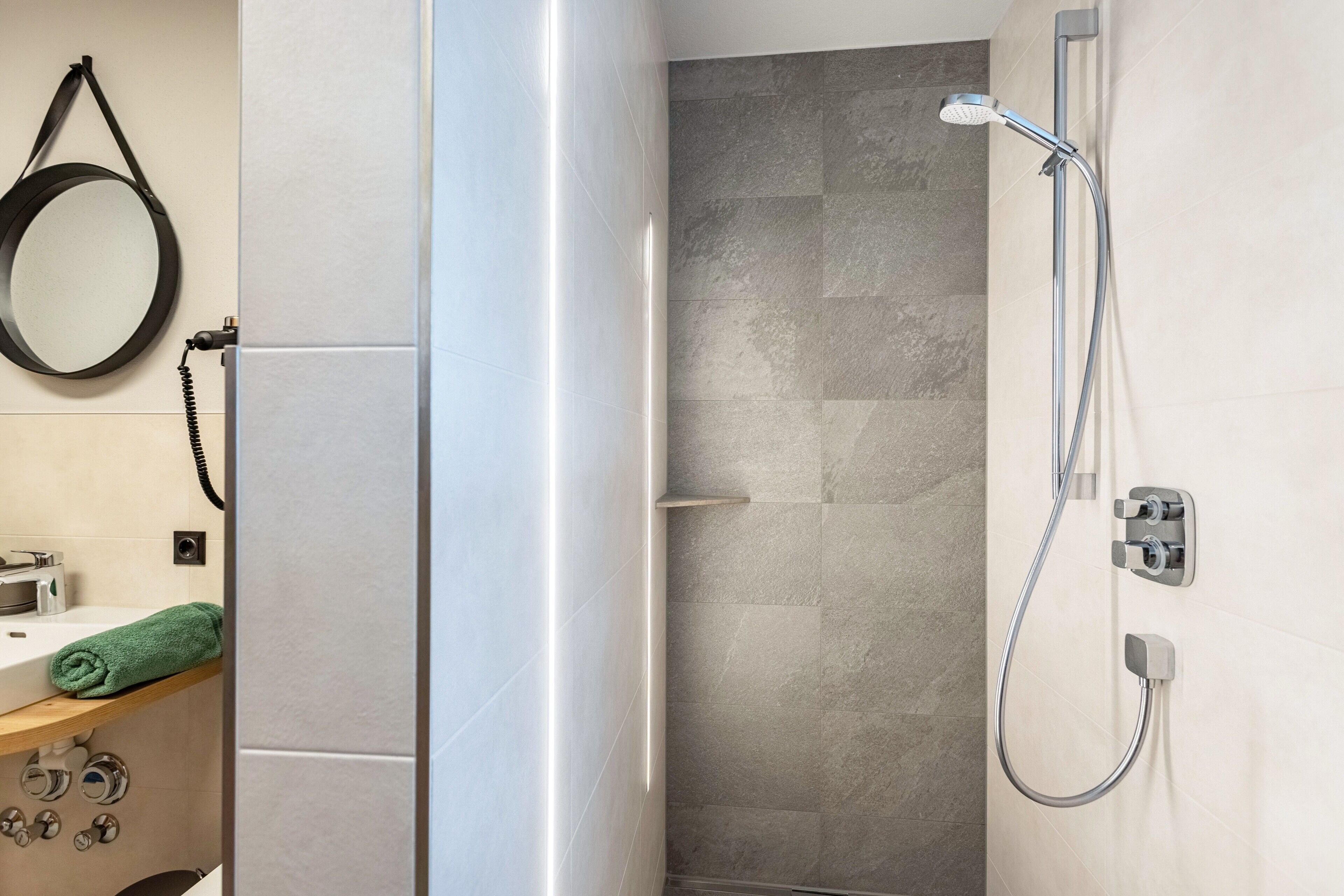 A bathroom with a shower, a towel rack, and a mirror.