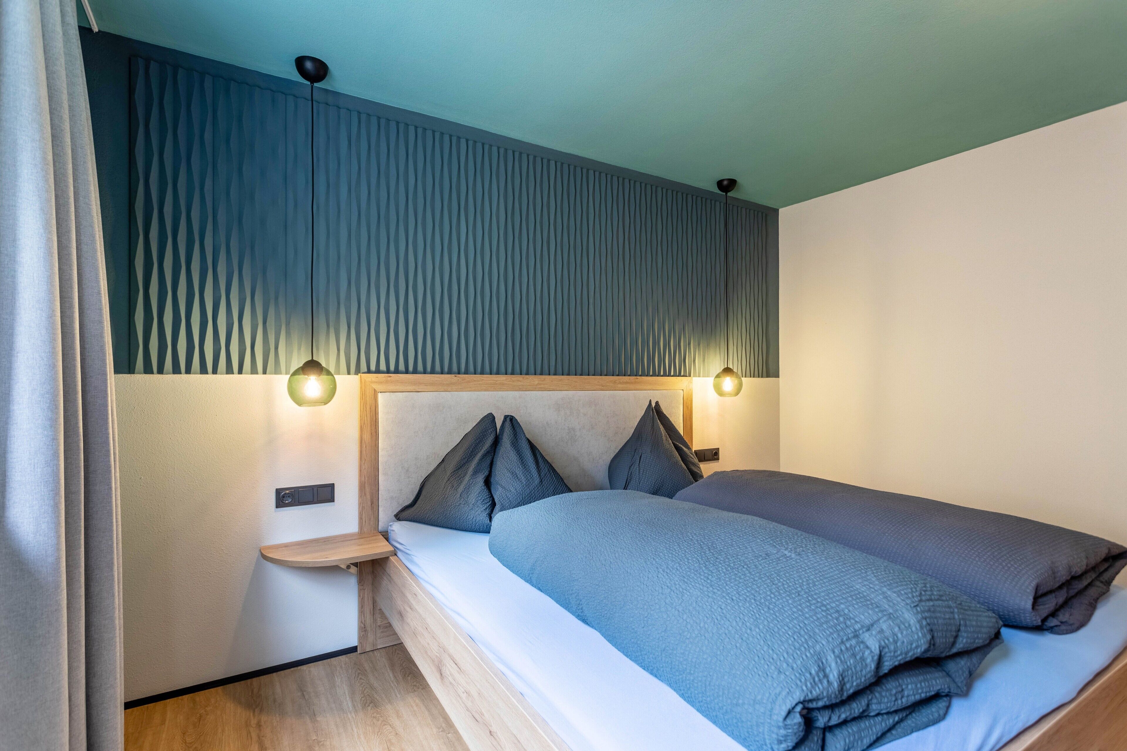 Een moderne slaapkamer met een bed, nachtkastjes en wandlampen.