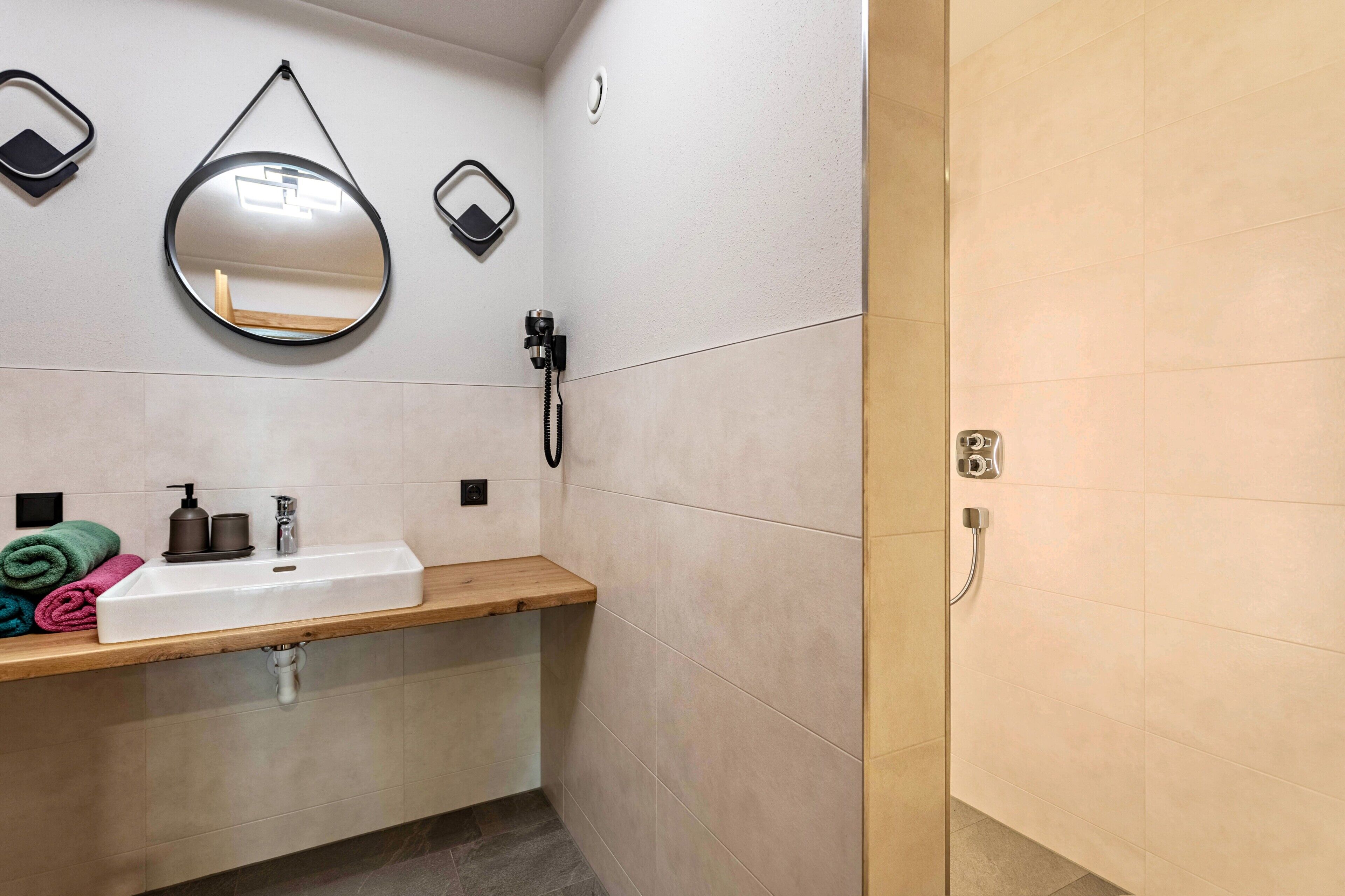 Ein Badezimmer mit Waschbecken, Spiegel, Handtuchhalter und Dusche.