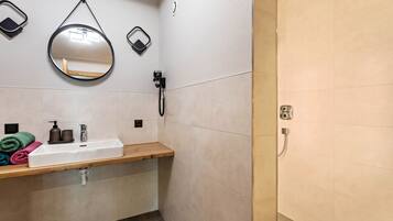 Ein Badezimmer mit Waschbecken, Spiegel, Handtuchhalter und Dusche.