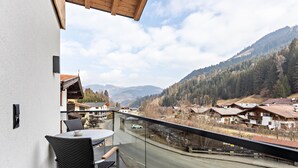 A balcony with a table and chairs, overlooking a road and a mountainous landscape. - Apartment 'Luisalle Top 6' with Mountain View, Balcony and Wi-Fi (Auffach)