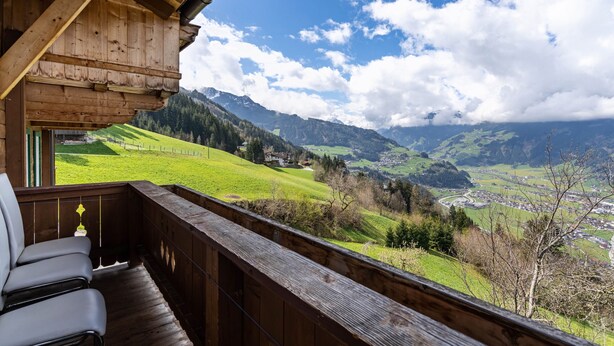A wooden balcony with a view of a valley, mountains, and a small town. - Apartment 'Unterlehenhof A' with Mountain View, Balcony and Wi-Fi (Zell am Ziller)