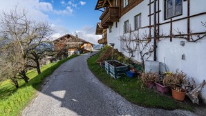 A narrow paved path leading to a traditional building with wooden balconies and a white exterior. - Apartment 'Unterlehenhof A' with Mountain View, Balcony and Wi-Fi (Zell am Ziller)