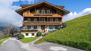 A multi-story wooden building with a balcony, a front porch, and a clear sky. - Apartment 'Unterlehenhof A' with Mountain View, Balcony and Wi-Fi (Zell am Ziller)
