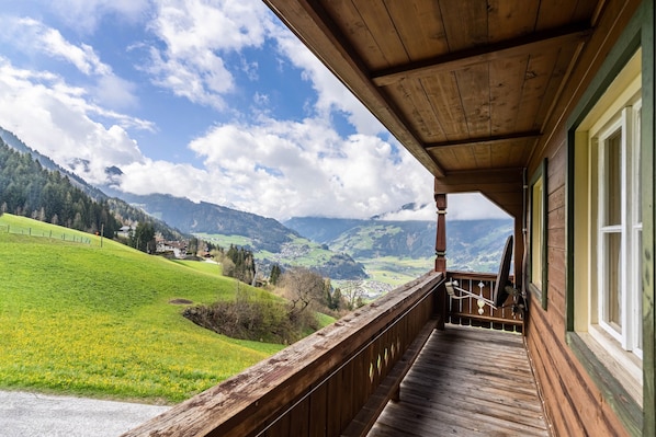 Un balcón de madera con vistas a un valle verde y montañas.
